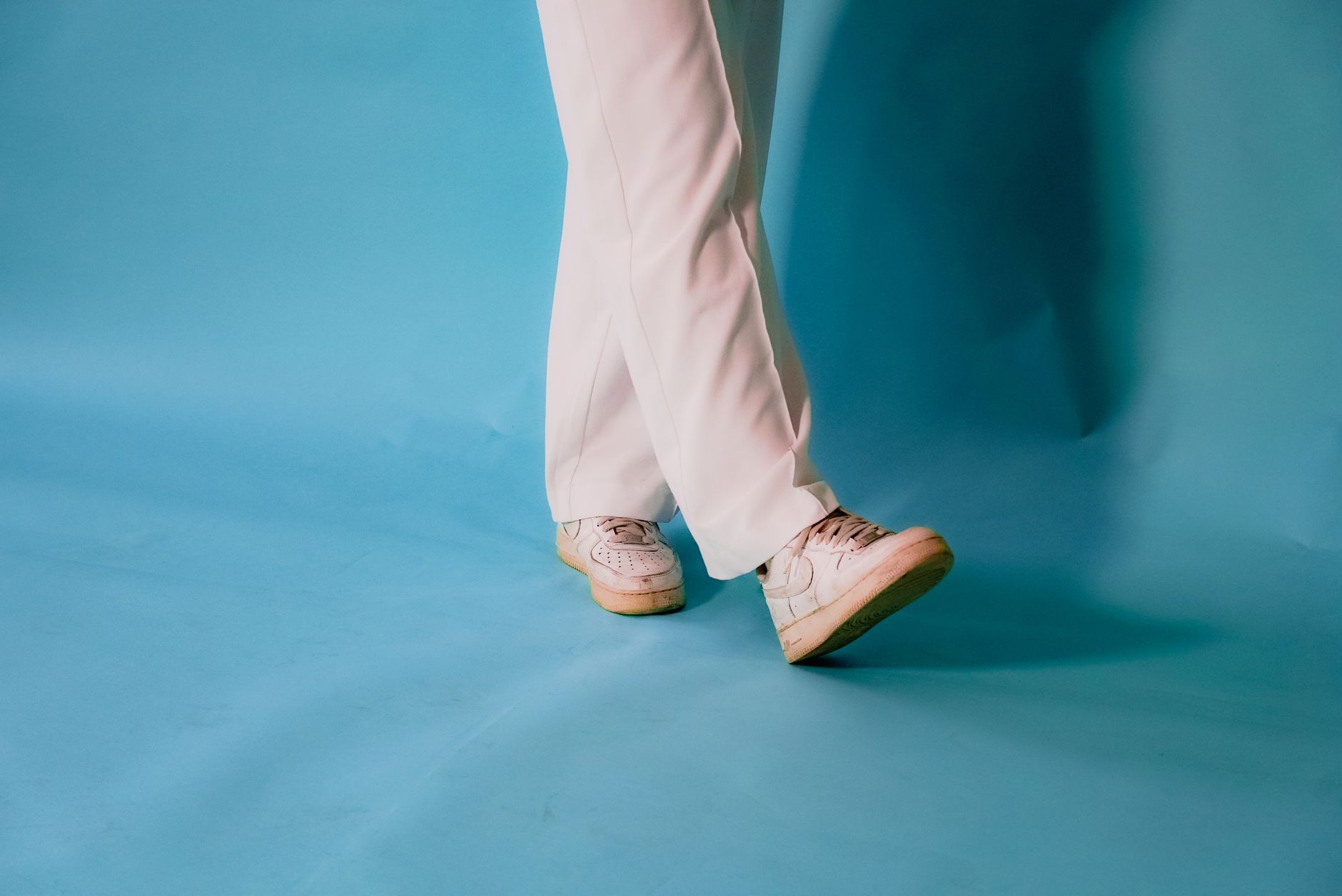 Białe sneakersy i białe spodnie na niebieskim tle