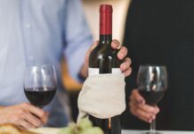 Jak serwować wino do wegańskiej kolacji: praktyczne połączenia smaków i gotowe inspiracje Dwie osoby piją czerwone wino przy stole, butelka owinięta w płótno